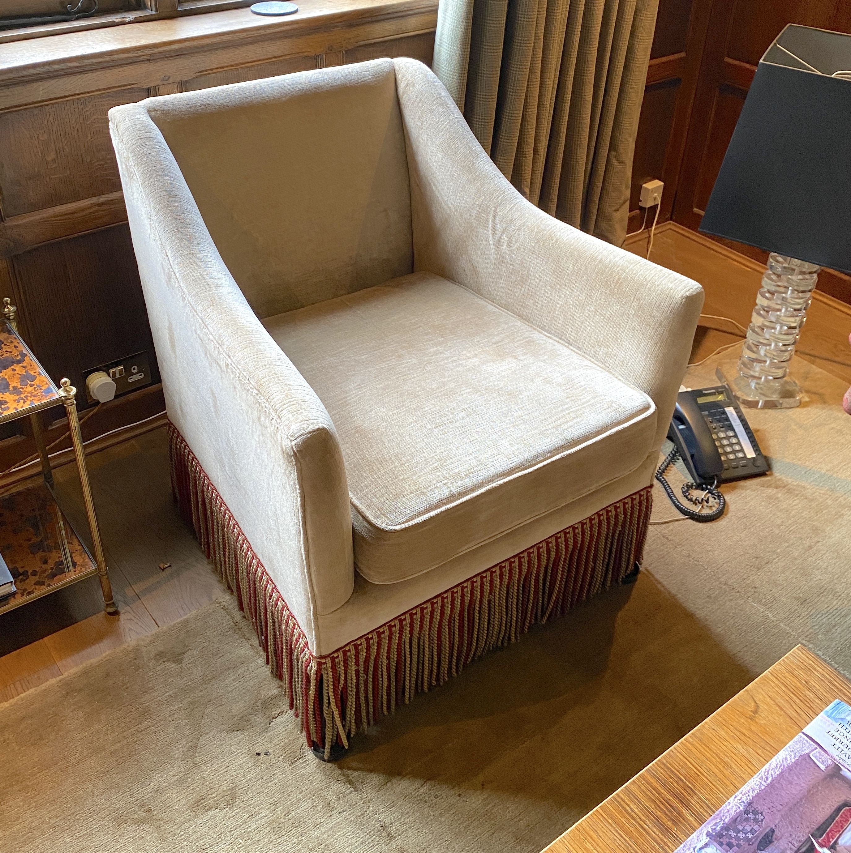 A pair of pale beige chenille armchairs, with tassle fringes, width 77cm depth 80cm